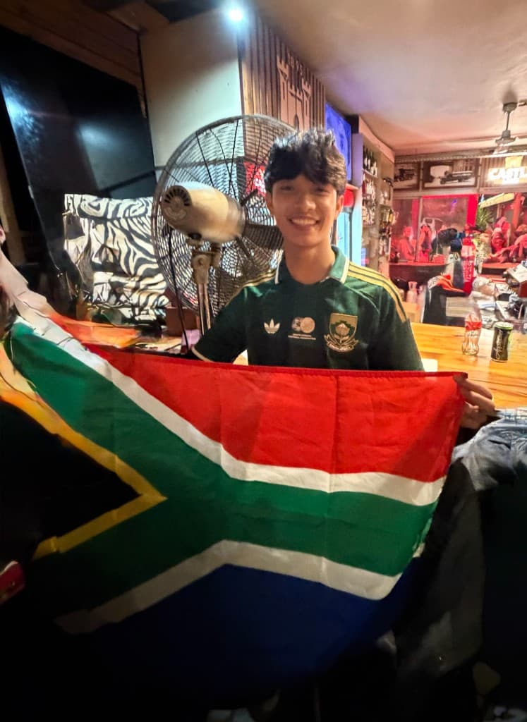 Holding up a South African flag while watching a match